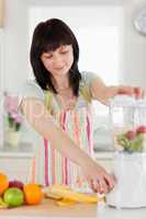 Pretty brunette woman using a mixer while standing