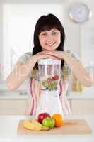 Pretty brunette woman posing with a mixer while standing