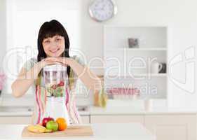 Attractive brunette woman posing with a mixer while standing