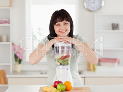 Good looking brunette woman posing with a mixer while standing