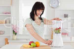 Cute brunette woman using a mixer while standing