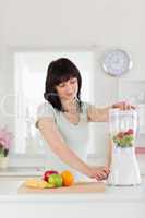 Cute brunette female using a mixer while standing