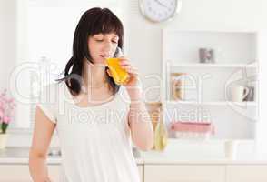 Lovely brunette drinking a glass of orange juice while standing