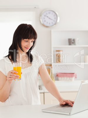 Good looking brunette woman holding a glass of orange juice whil