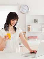 Good looking brunette woman holding a glass of orange juice whil