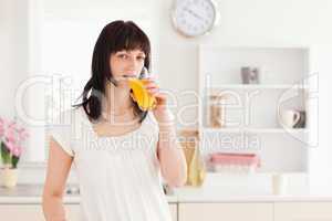 Gorgeous brunette drinking a glass of orange juice while standin