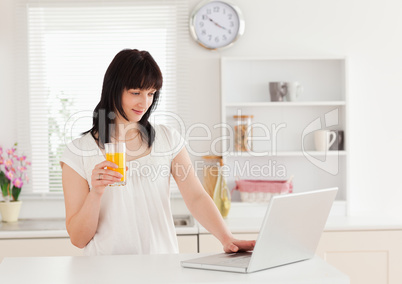 Beautiful brunette woman holding a glass of orange juice while r