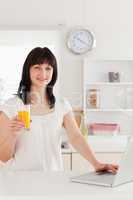 Cute brunette woman holding a glass of orange juice while relaxi