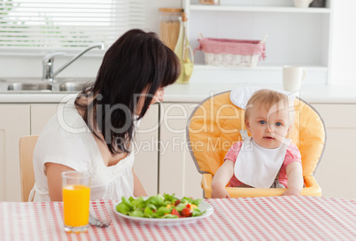 Attractive brunette woman having a meal with her baby while sitt