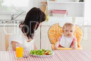 Attractive brunette woman having a meal with her baby while sitt
