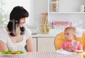 Gorgeous brunette woman having a meal with her baby while sittin
