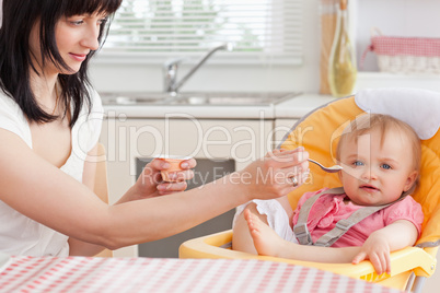 Attractive brunette woman feeding her baby while sitting