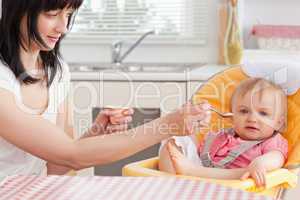 Attractive brunette woman feeding her baby while sitting