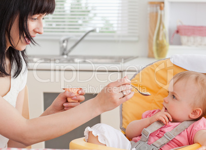 Beautiful brunette woman feeding her baby while sitting