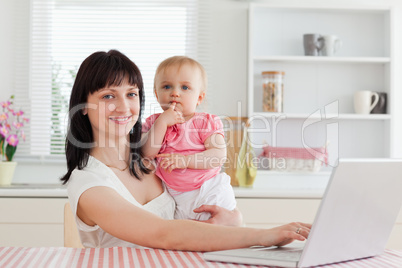 Lovely brunette woman relaxing with her laptop next to her baby