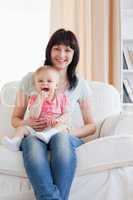 Attractive woman holding her baby in her arms while sitting on a