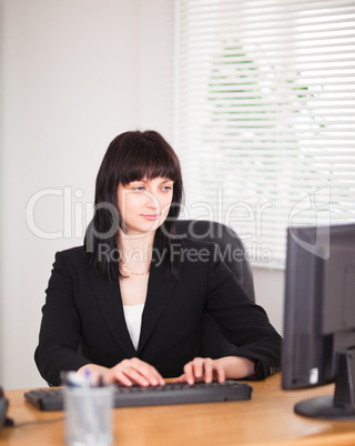 Attractive brunette woman working on a computer while sitting at