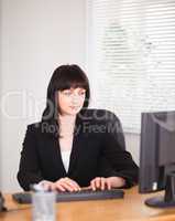 Attractive brunette woman working on a computer while sitting at