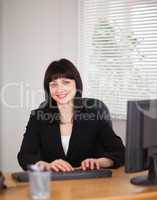 Good looking brunette woman working on a computer while sitting