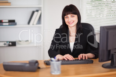 Pretty brunette woman working on a computer while sitting at a d