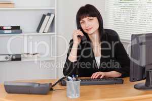 Pretty brunette woman on the phone while working on a computer