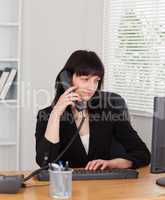 Beautiful brunette woman on the phone while working on a compute