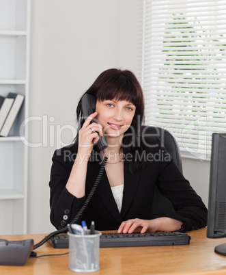 Good looking brunette woman on the phone while working on a comp