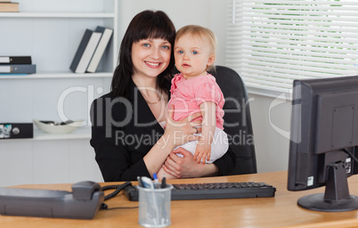 Good looking brunette woman posing while holding her baby on her