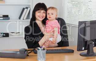 Good looking brunette woman posing while holding her baby on her