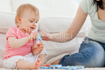 Female showing a puzzle piece to her baby while sitting on a car