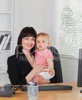 Attractive brunette woman posing while holding her baby on her k