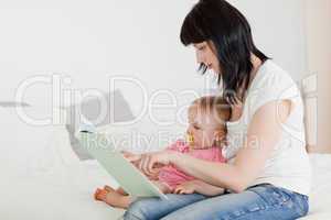 Lovely brunette woman showing a book to her baby while sitting o