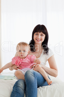 Attractive brunette woman holding her baby on her knees while si