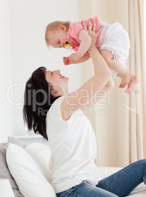 Attractive brunette woman playing with her baby while sitting on