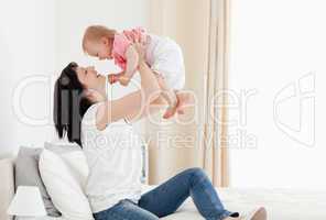 Good looking brunette woman playing with her baby while sitting