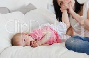 Good looking brunette female playing with her baby while lying o
