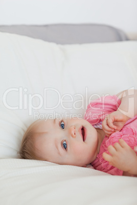 Lovely blond baby lying on a bed