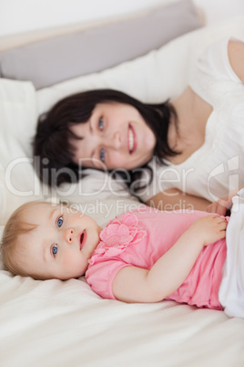Attractive brunette female posing with her baby while lying on a