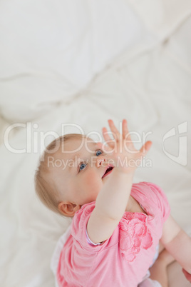 Cute baby wanting to catch something while sitting on a bed