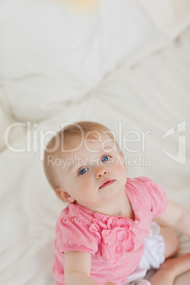 Cute baby looking at the camera while sitting on a bed