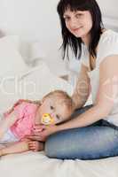 Attractive brunette female posing with her baby lying on her