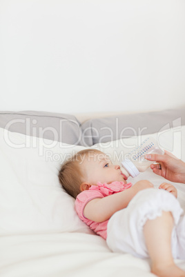 Female hand bottle-feeding her baby on a bed