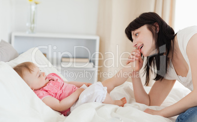 Good looking brunette female playing with her baby while sitting
