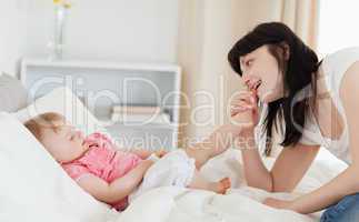 Good looking brunette female playing with her baby while sitting