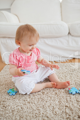Baby playing with puzzle pieces while sitting on a carpet