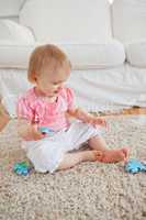 Baby playing with puzzle pieces while sitting on a carpet