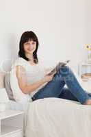 Good looking brunette woman reading a book while sitting on a be