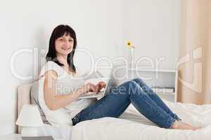 Beautiful brunette woman relaxing with her laptop while sitting