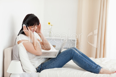 Charming brunette woman relaxing with her laptop while sitting o