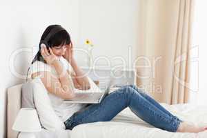 Charming brunette woman relaxing with her laptop while sitting o